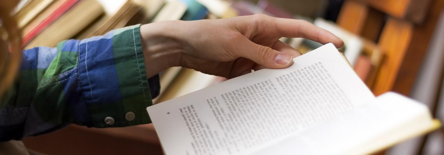 close up of a hand turning pages of a book